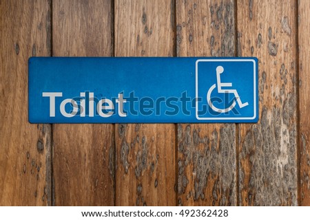 handicapped toilet sign on wooden door