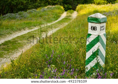 Quarter column in the wood - boundary post in a forest. The dirt road on forest area border, trees and the wood, a quarter column. Border area in deep forest.
