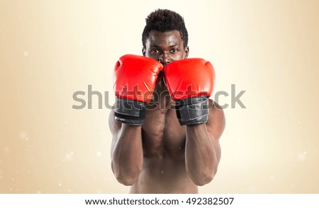 Handsome black man with boxing gloves over ocher background