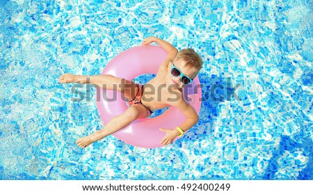Little boy with pink rubber ring in swimming pool