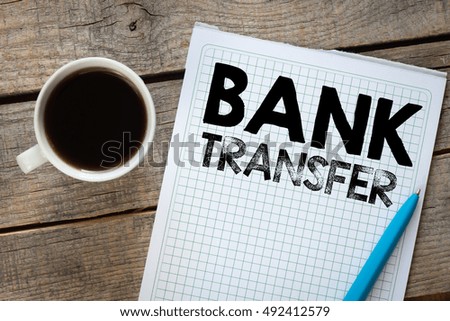 Bank transfer./ Word bank transfer notepad, pen and cup of coffee on board.