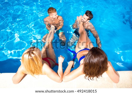 A group of young friends having fun in a swimming pool.
