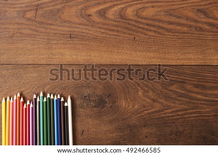 Colorful pencils on the brown wooden table background. Frame of colored pencils over wood with free space for text, copy space