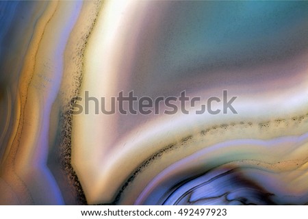 Macro shot of Geode slice.  Colorful stone with light shining through to show translucent design. Royalty-Free Stock Photo #492497923