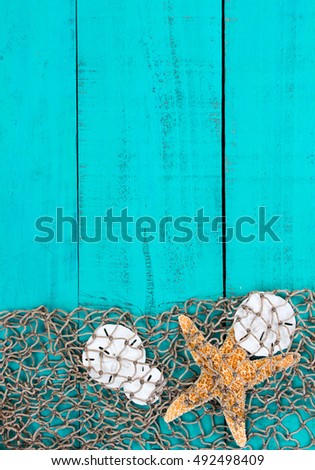 Blank antique rustic wood sign with fish net and seashells border; background with teal blue copy space 