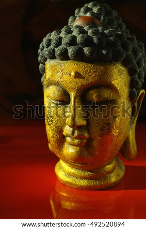Gold Buddha face on dark red background