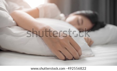 Cute girl on a soft white bed. She sleeping and relaxing. Royalty-Free Stock Photo #492556822