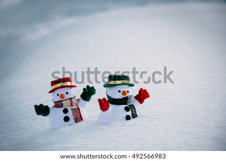 Snowman and friend stand among pile of snow in park. Morning sunshine is warming in winter. Welcome christmas season.