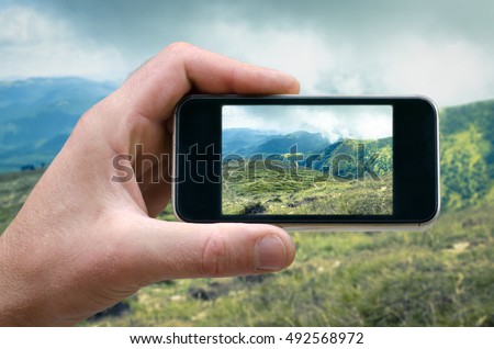 phone in hand man photographing the landscape photos from your phone, Selfie, photographing on the phone, the man photographs the mountain landscape on the phone smartphone side view. carpathians