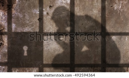 Thinking man Shadow Under Jail Bars. Royalty-Free Stock Photo #492594364