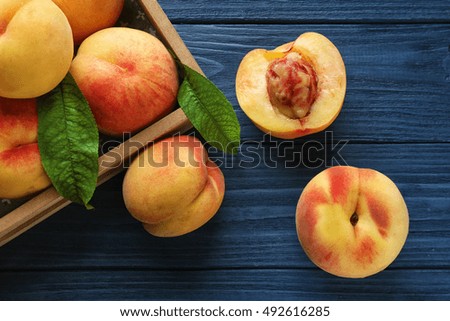 Fresh juicy peaches in tray on blue wooden background