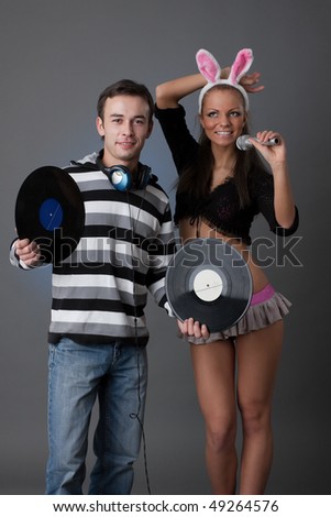Male DJ and beautiful girl with vinyl disks on a grey background
