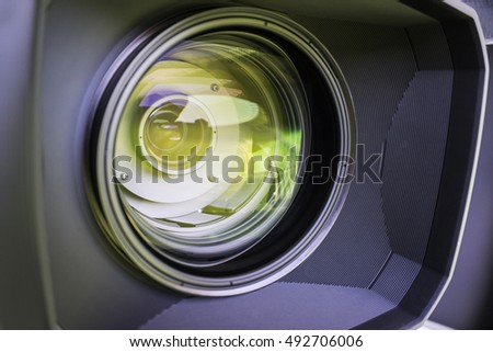 View of the glass elements in a camera lens. Objective under yellow light. Tilt-shift use.