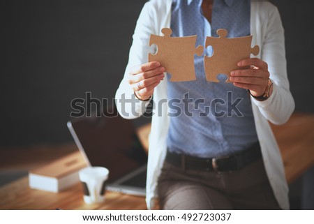 Business woman holding and pointing to a puzzle piece