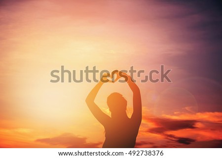 Women hands forming a heart with sunset silhouette 