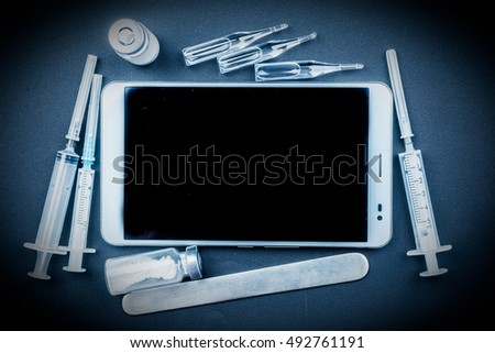 Tablet pc with medical objects on a desk as a metaphor for electronic diagnostic or healthcare mobile apps. Medical background