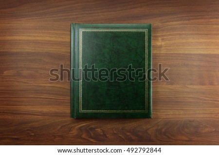 Green Photo album or Year book cover, blank, placed on a dark colored wooden table.