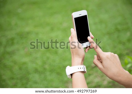 Women hand holding using mobile smart phone in the park