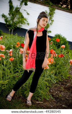 Teenage fashion girl with red scarf in a park with red poppies