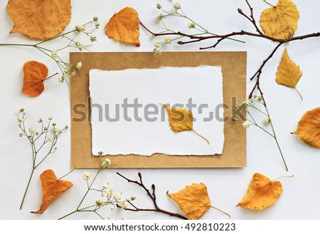 Autumn note. Craft empty paper card, yellow dried fall leaves, branches, flower. Natural decor background.