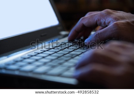 Selective focus on man two hand typing laptop/PC/computer keyboard in night dark tone low key