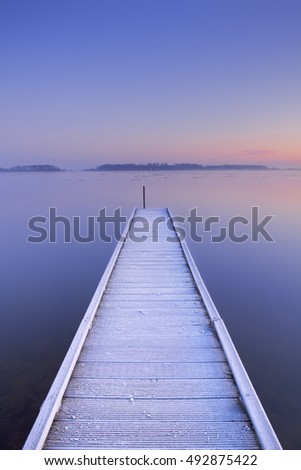 A quiet lake in The Netherlands with a jetty on an early winter morning.