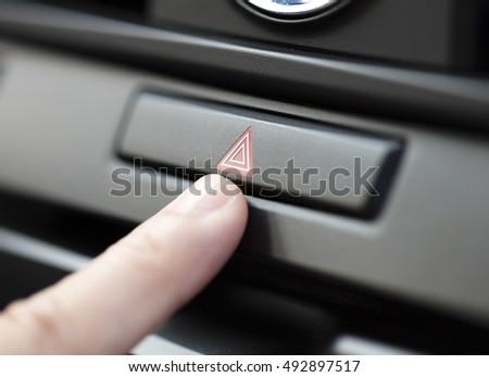 finger pressing car emergency light button