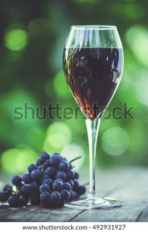 Glass with red wine on the wooden table. Shallow depth of field. Toned image.