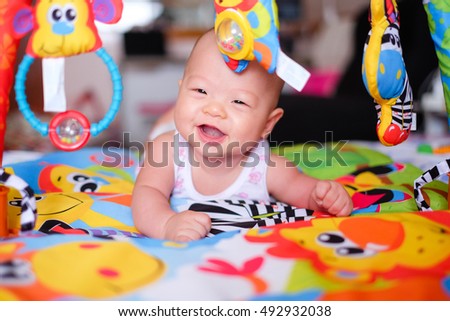 A happy asian baby boy at tummy time on the play gym on Bed in Bedroom at Home - Selective Focus