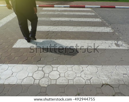  A man walking on crosswalk with in noon day light.         