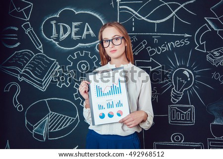 Portrait of a business woman in glasses on dark background with pictures charts in hand