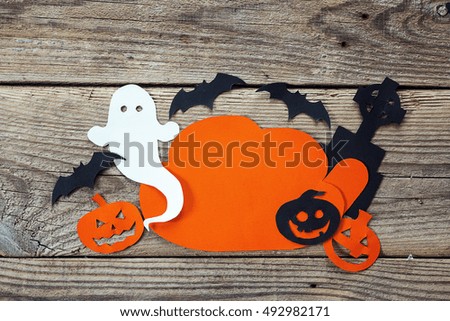 Cloud frame with ghost, pumpkin, bats, headstone cut out of paper. Happy Halloween card. Background of old wooden boards.