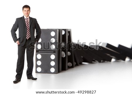 Businessman near a stack of dominoes. Isolated on white background