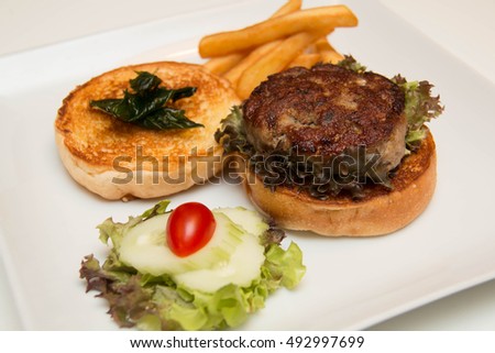 burger And Fries with vegetables in white dish.
