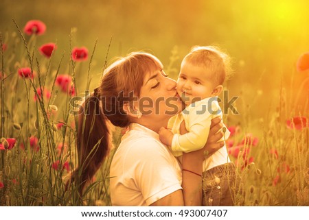 Mother and daughter with red poppies, a child in a field of flowers.