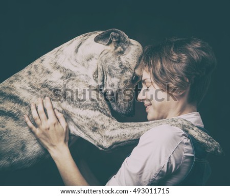 portrait of a beautiful young woman with a  dog on a dark background. High quality, photographed in the studio.
