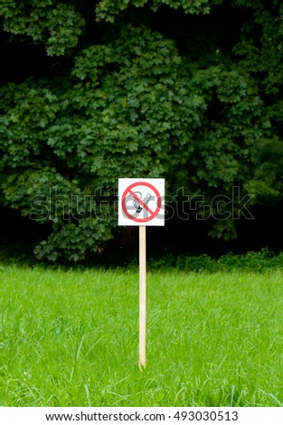 No smoking sign in the park on bright green trees and grass background.