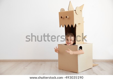 Little boy playing with cardboard box on white wall background Royalty-Free Stock Photo #493035190