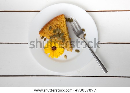 Pumpkin cake decorated with flower on white wooden background