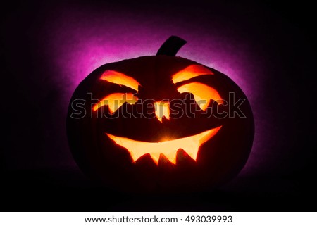 Halloween pumpkin head jack lantern with burning candles on purple background