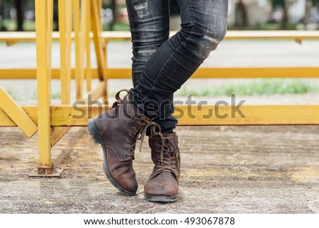 Men fashion, man's legs in black jeans and brown leather boots. Toned picture.