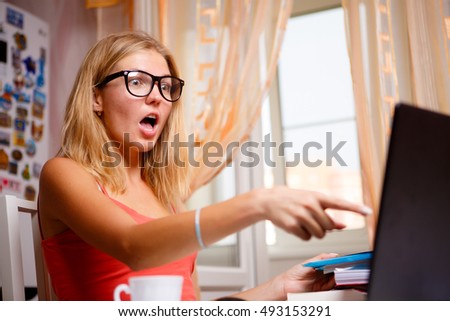 Portrait indoor of stunned student girl in glasses showing something on screen