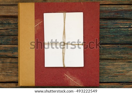 Vintage red photo album or photo book with vintage style stack of blank photos on a rustic wood background