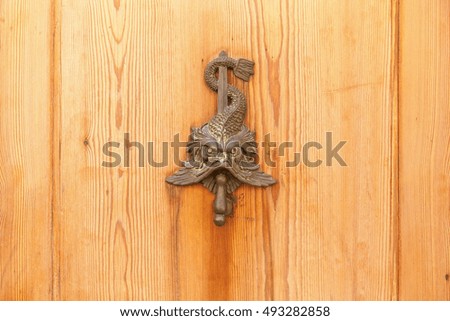 Wood door. Close up of the wooden door with the metal picture of the mystical animal with the sword. 
