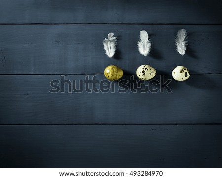Quail eggs with feathers on the table of the old blue wooden boards