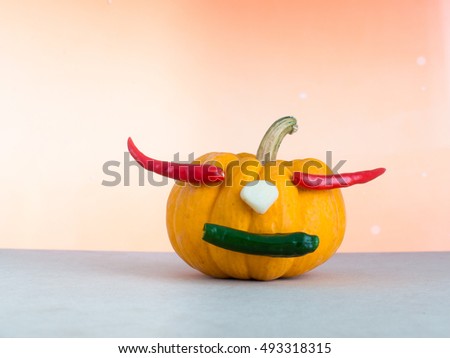 pumpkin on orange background, red chili in pumpkin, yellow pumpkin make mouth by green chili, garlic on yellow pumpkin,