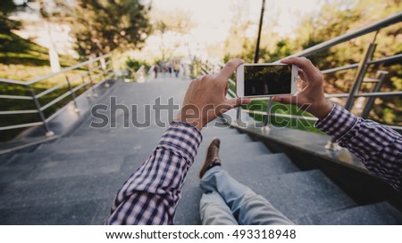 Close up a man taking photos of nice view with his smart phone while sitting on stairs