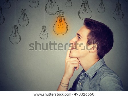 Thinking man looking up with light idea bulb above head isolated on gray wall background
