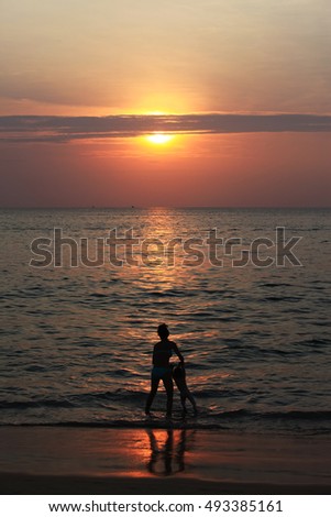 happy kids playing and swim with mom on the beach at sunset