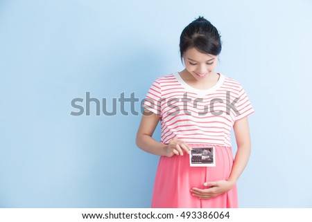 pregnant woman take ultrasound picture and smile isolated on bluebackground, asian